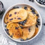 top view of blueberry lemon ricotta pancakes on a round white plate