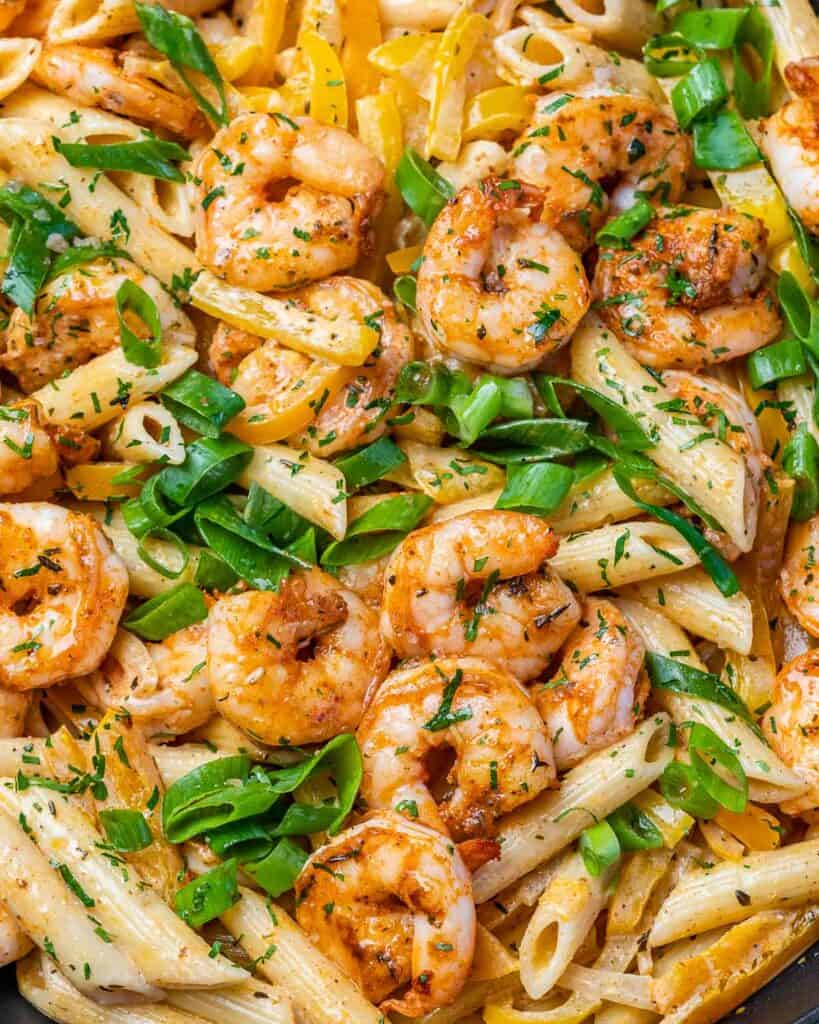 close up view of shrimp jamaican style shrimp pasta made with penne pasta and topped with sliced green onions