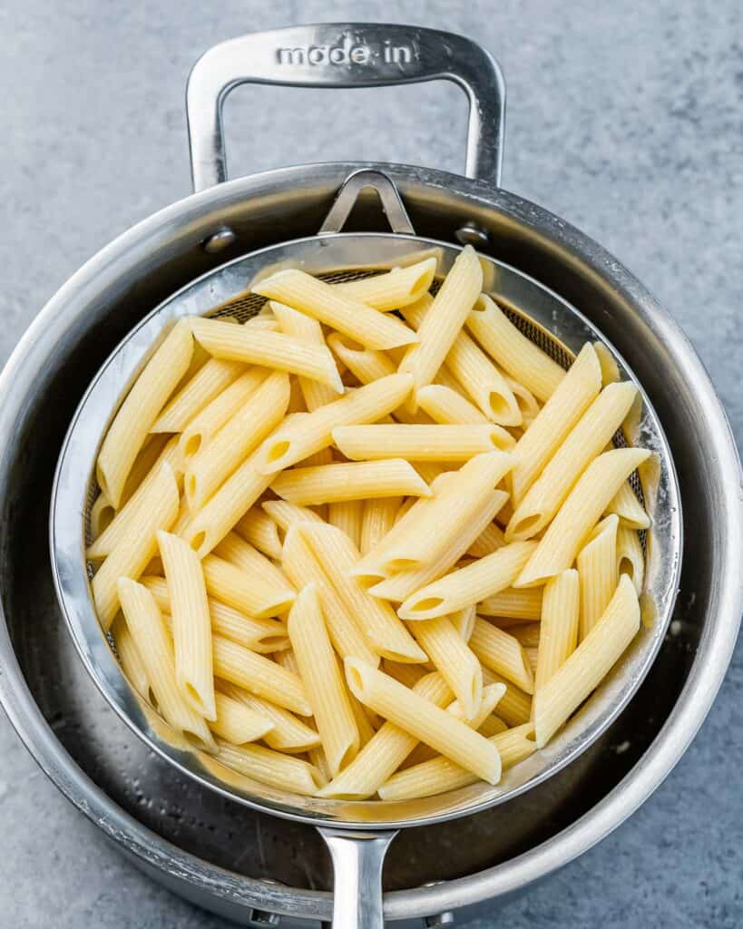 cooked penne pasta on a colander to cool off
