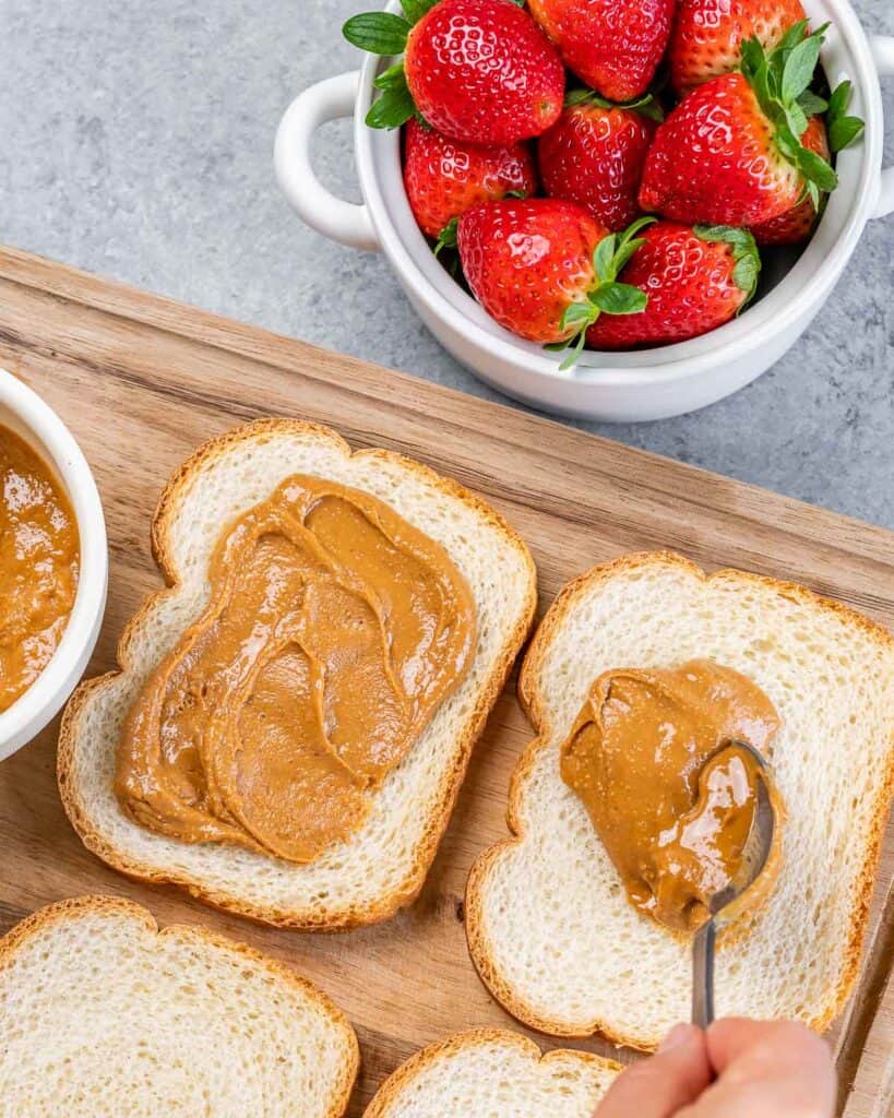 Spreading peanut butter on slices of bread.