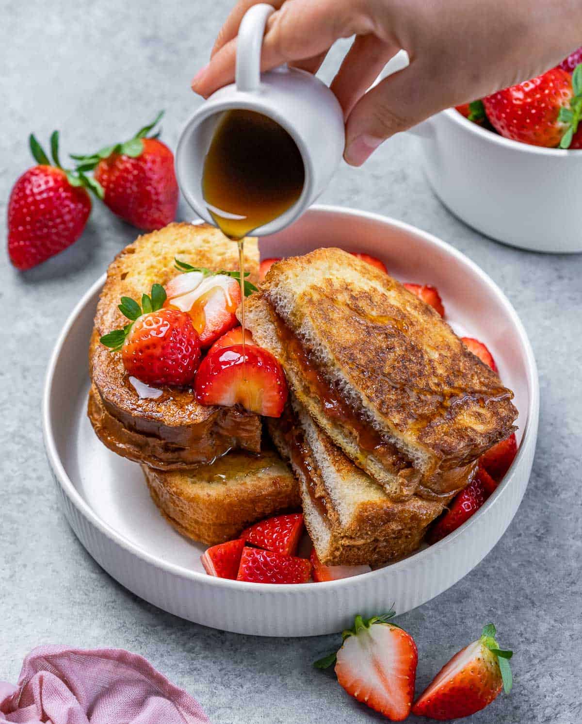 Drizzling maple syrup over the top of stuffed French toast.