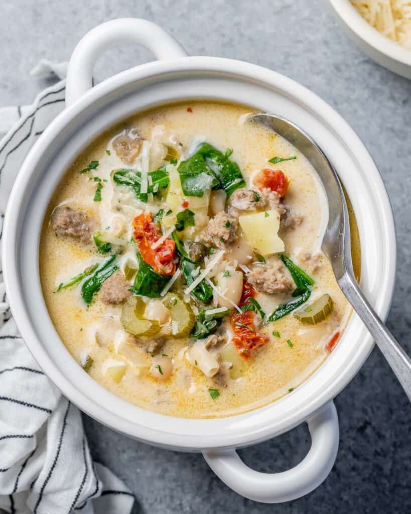 Spoon in a white bowl with a creamy Tuscan white bean soup.