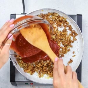 Adding the tomato sauce over the seared veggies.