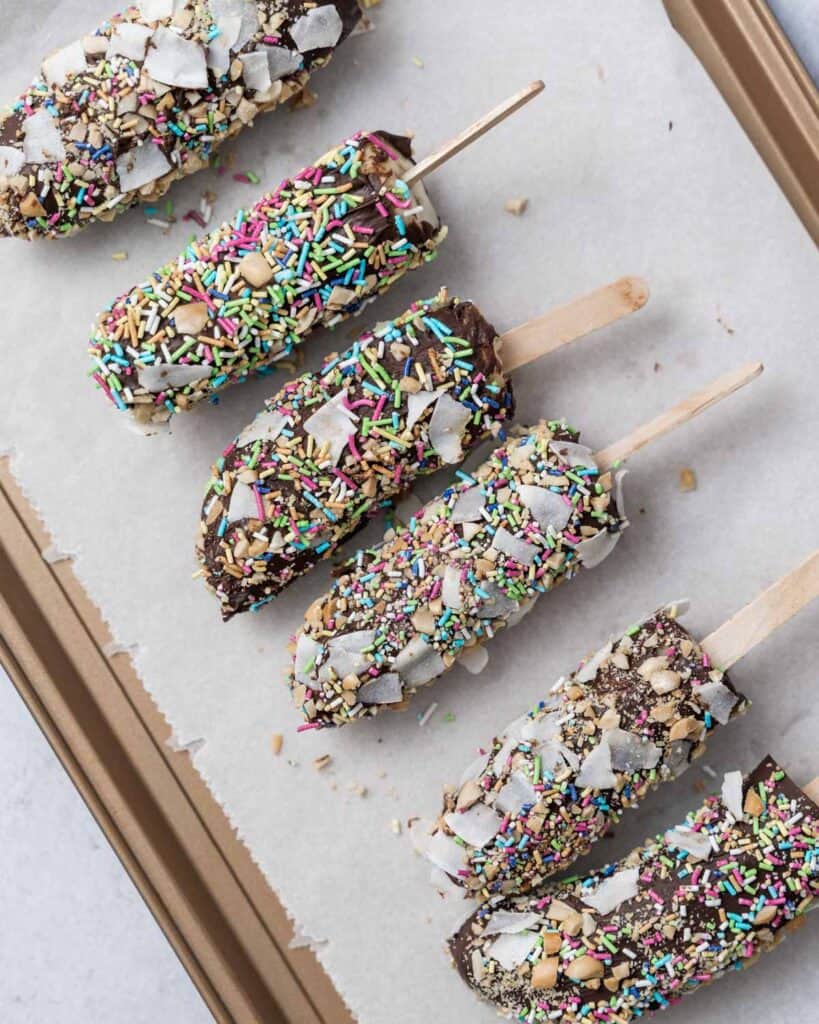 banana pops topped with sprinkles over parchment paper