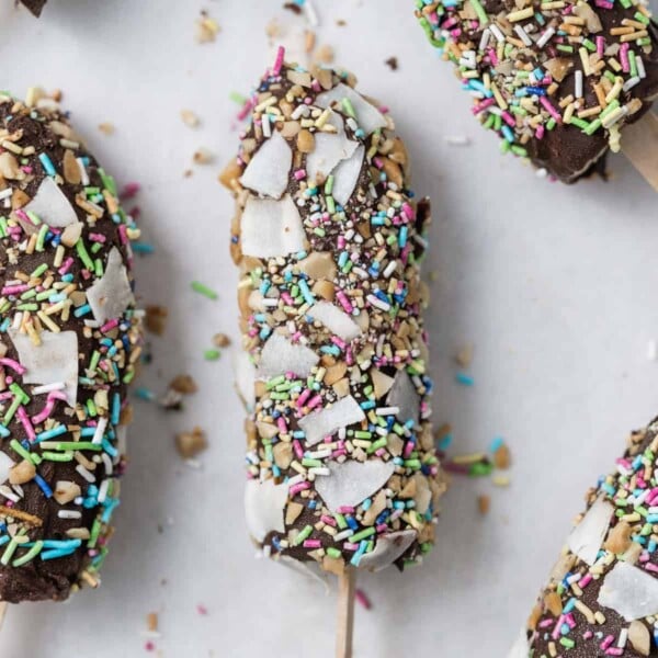 top view of a single banana popsicle covered in chopped peanuts, sprinkles, and shaved coconut flakes