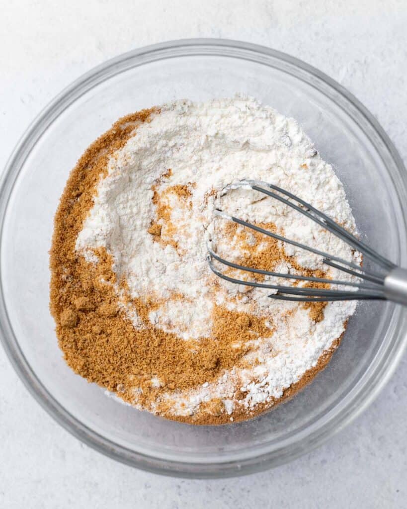 Using a whisk to mix flour with sugar and spices.