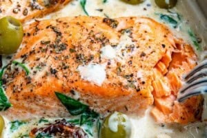 Fork flaking a salmon fillet in the pan.