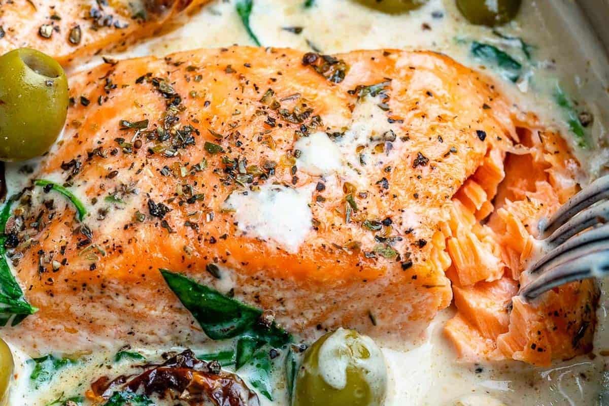 Fork flaking a salmon fillet in the pan.