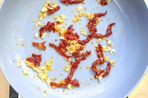 seared sun-dried tomatoes and garlic in a skillet.