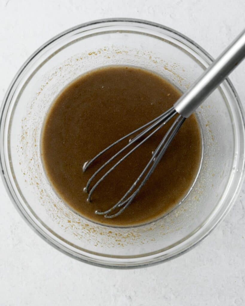 Whisking molasses with sugar, eggs, milk, oil and applesauce.