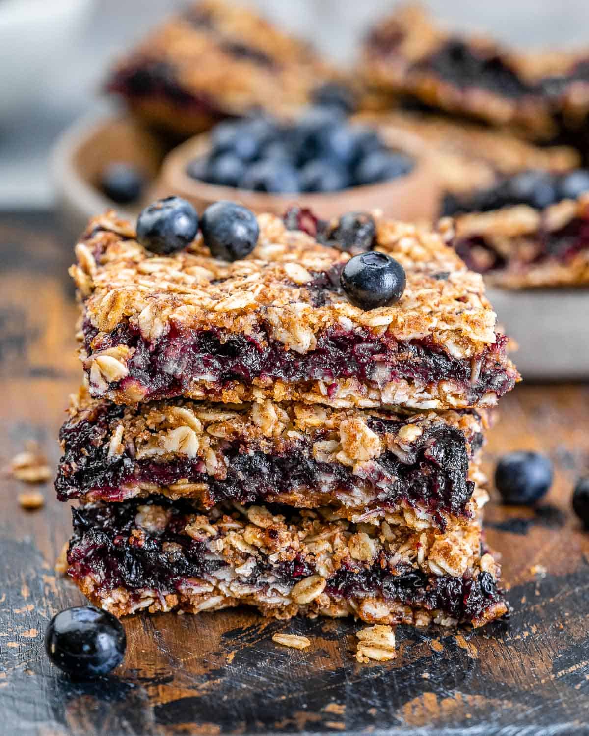 3 oatmeal bars stacked over each other on a cutting board.