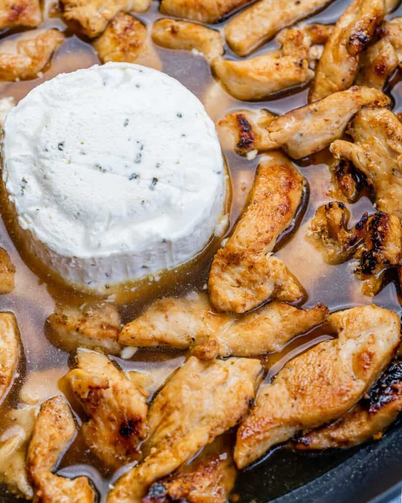 boursin cheese with cooked sliced chicken on a skillet before mixing 