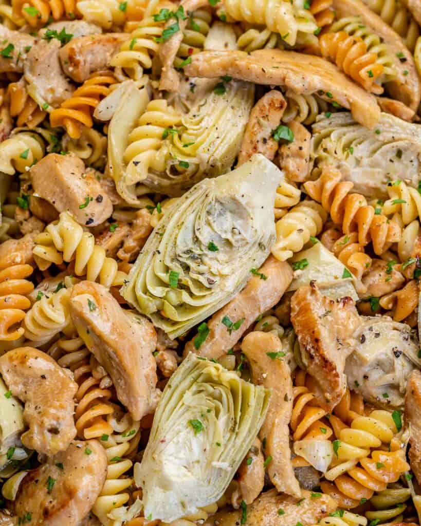 close image of pasta with artichokes and chicken in a pan