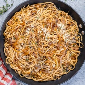 top view black skillet of brown pasta with caramelized onions and mushrooms