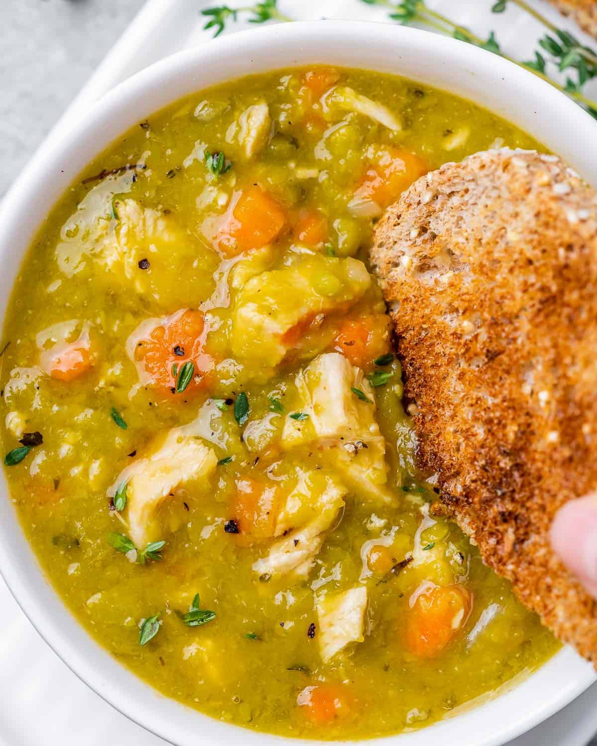 Dipping toast into a bowl of split pea soup.
