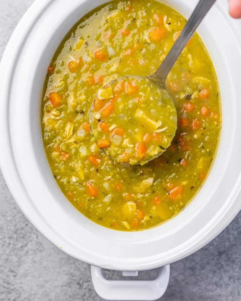 Ladling out slow cooker split pea soup from a crockpot.