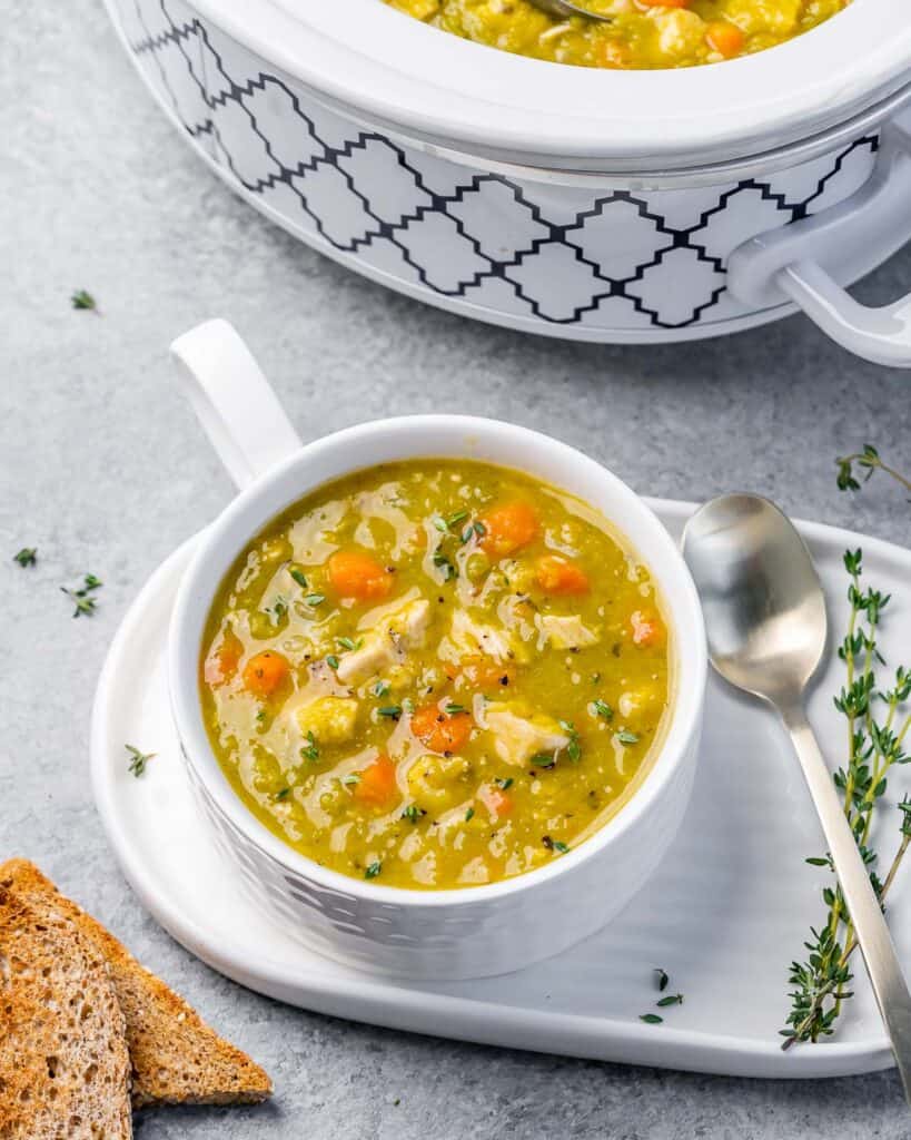 Pea soup with chicken and carrots in a white bowl.