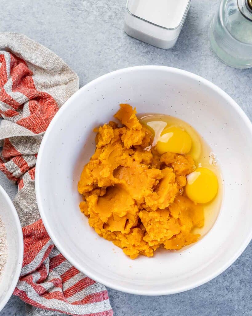 Mashed sweet potatoes and eggs in a large white bowl.