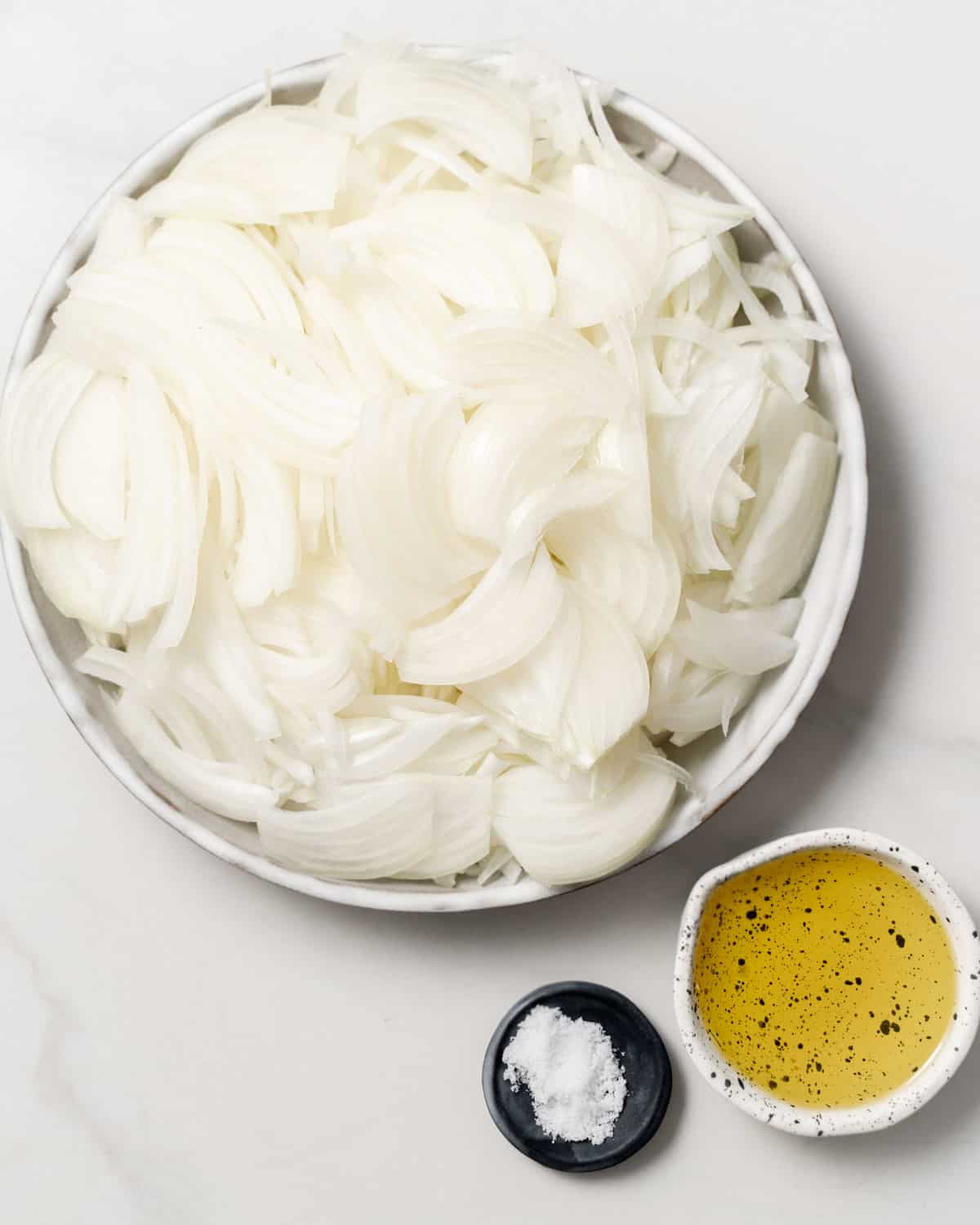 ingredients for making caramelized onions. a plate of sliced onions, salt, and olive oil