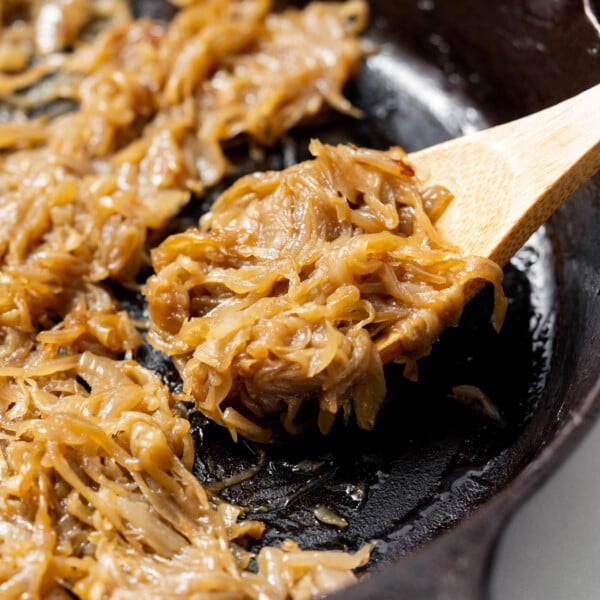 side shot of a pan with wooden spoon grabbing caramelized onions from pan