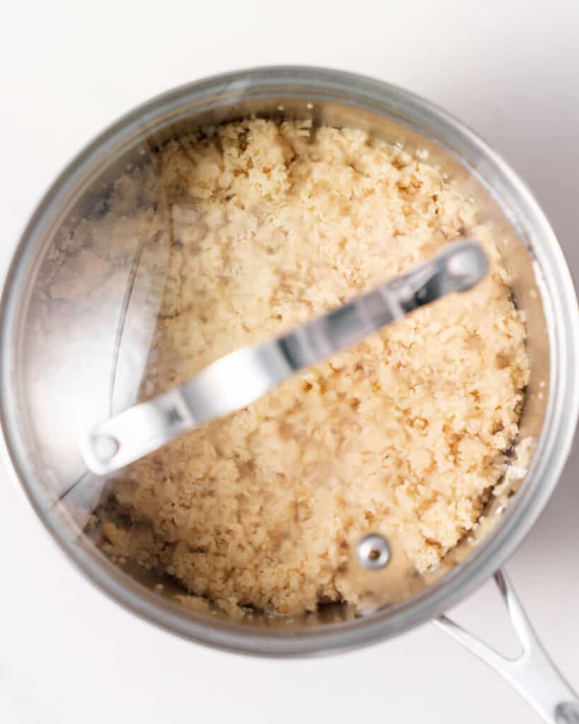 Couscous absorbing water in a covered pot.