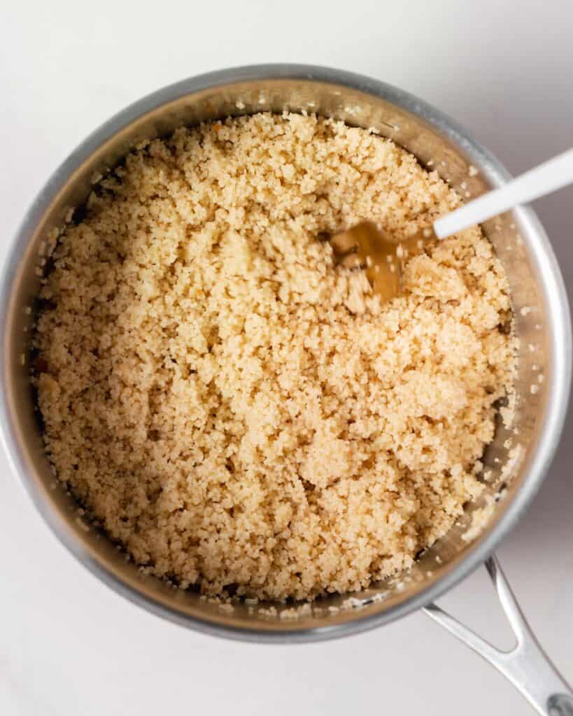 Fluffing cooked couscous with a fork.