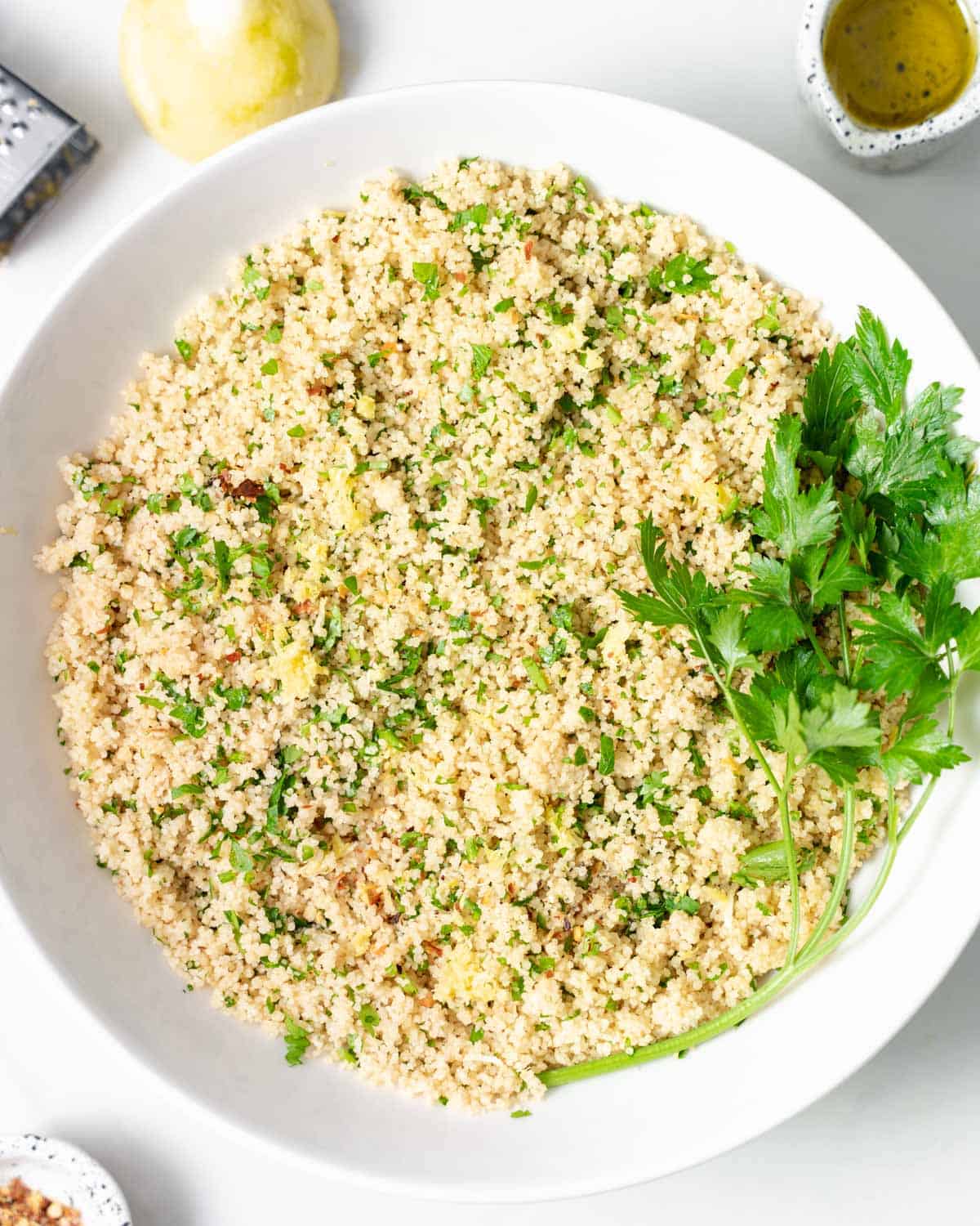 Couscous served in a white bowl garnished with fresh parsley.