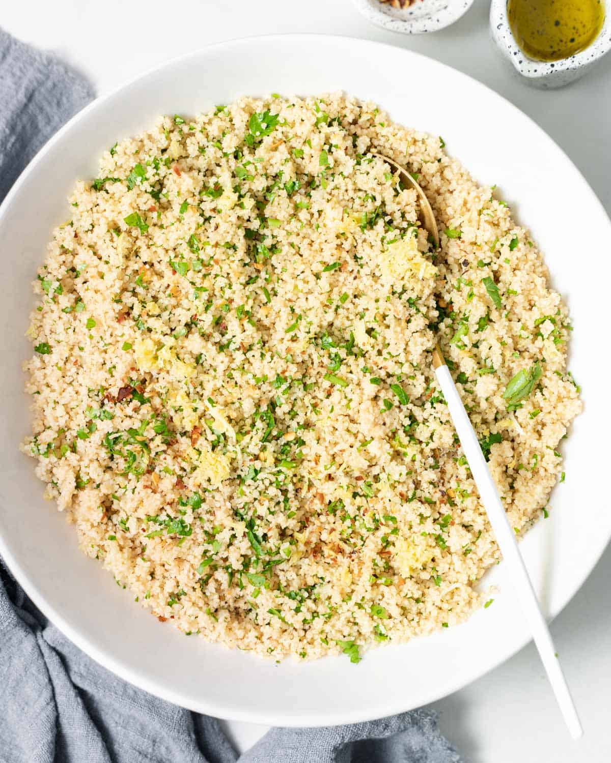 Couscous garnished with herbs and served with a large serving spoon.