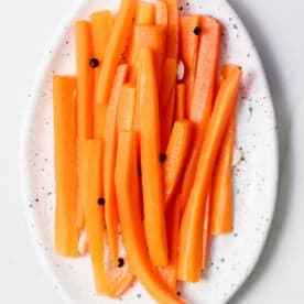 top view of pickled carrot sticks on an oval white plate