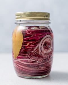 a jar with red onions and brine to be placed in the fridge.