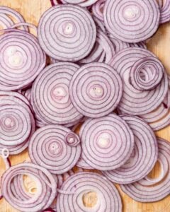 sliced red onion in rounds on a cutting board.