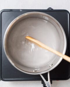 mixing the water vinegar and sugar in a pot and heating it up.