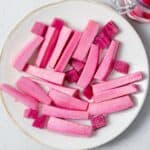 top view pickled pink turnip sticks on a white round plate