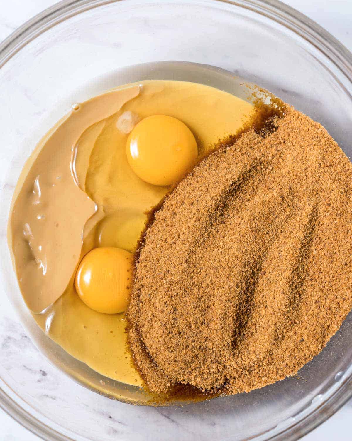 coconut sugar added over melted butter and 2 eggs in a clear bowl.