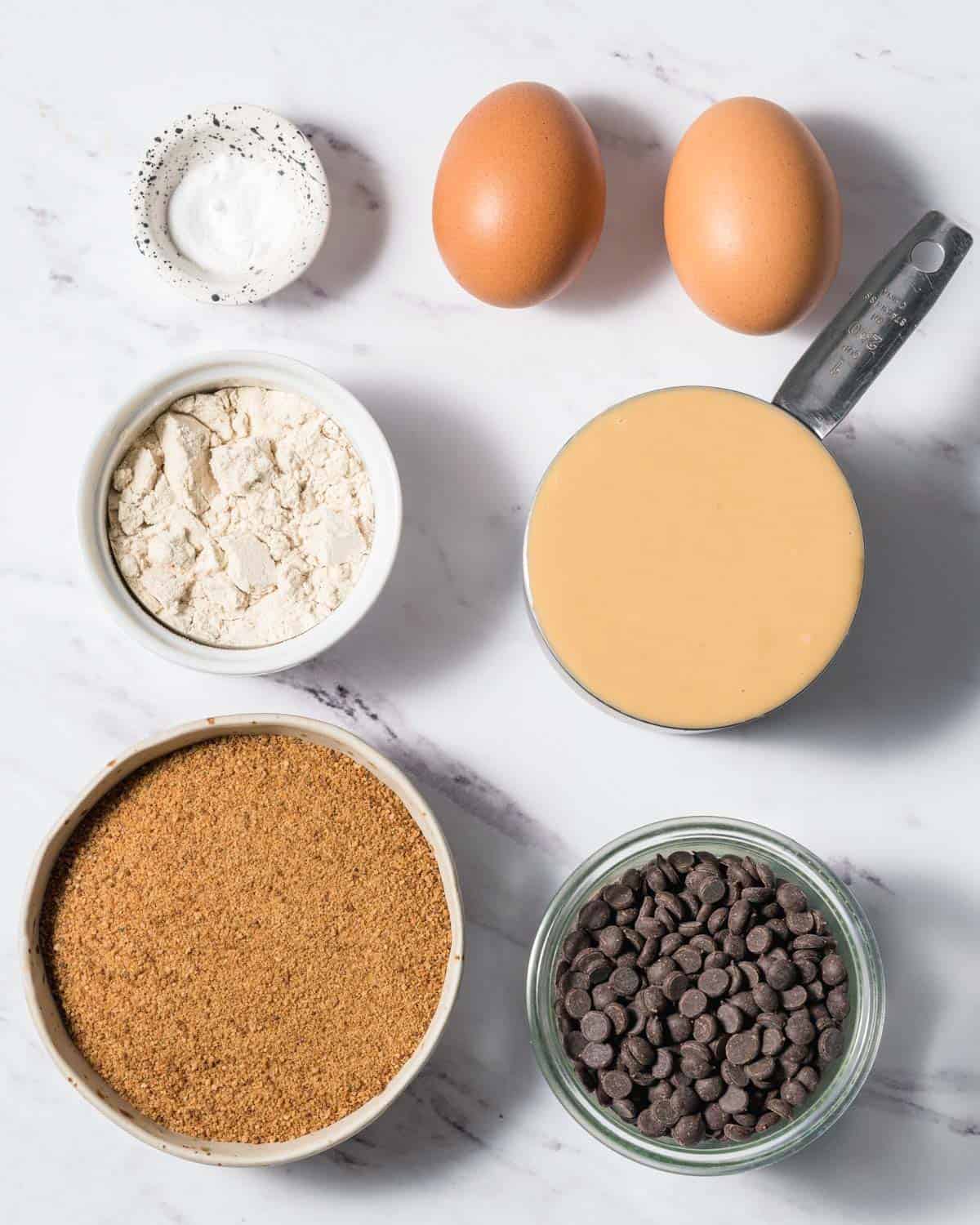ingredients to make peanut butter cookies: 2 eggs, protein powder, coconut sugar, chocolate chips, peanut butter, and baking soda.