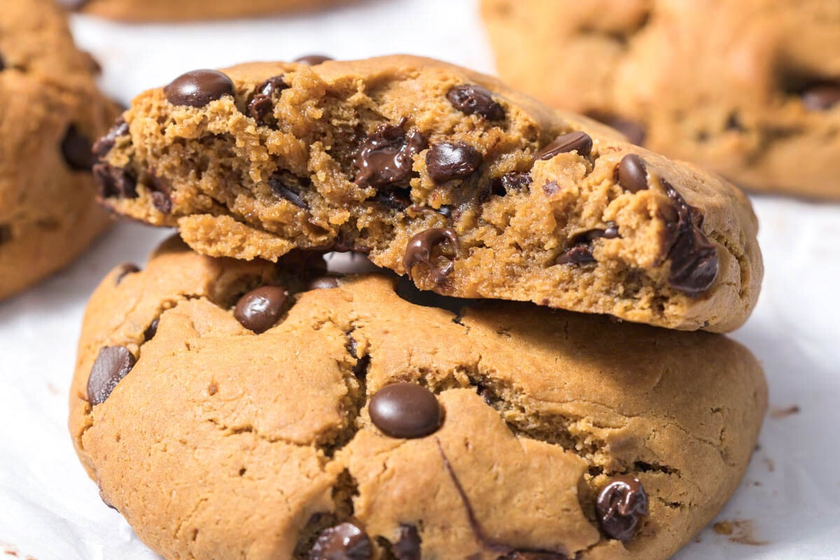 two peanut butter cookies stacked over each other with a bite taken off the top one.