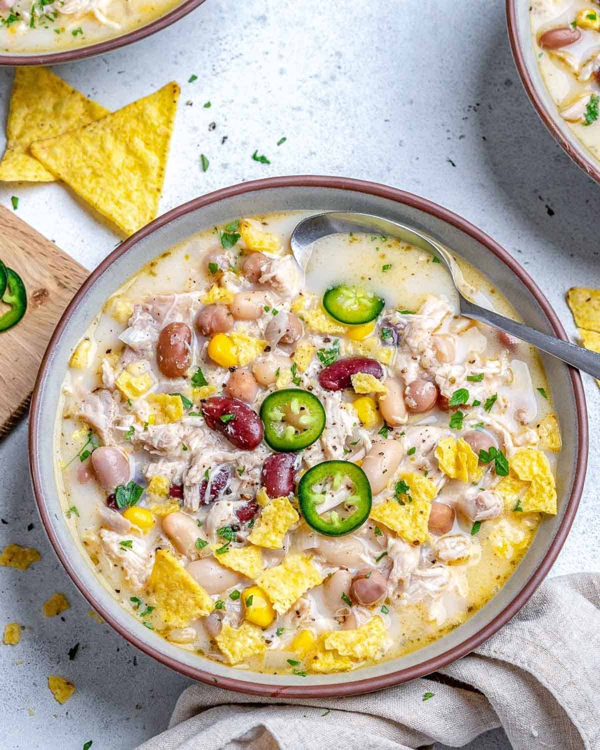 a bowl with white chicken chili and a spoon in the bowl.