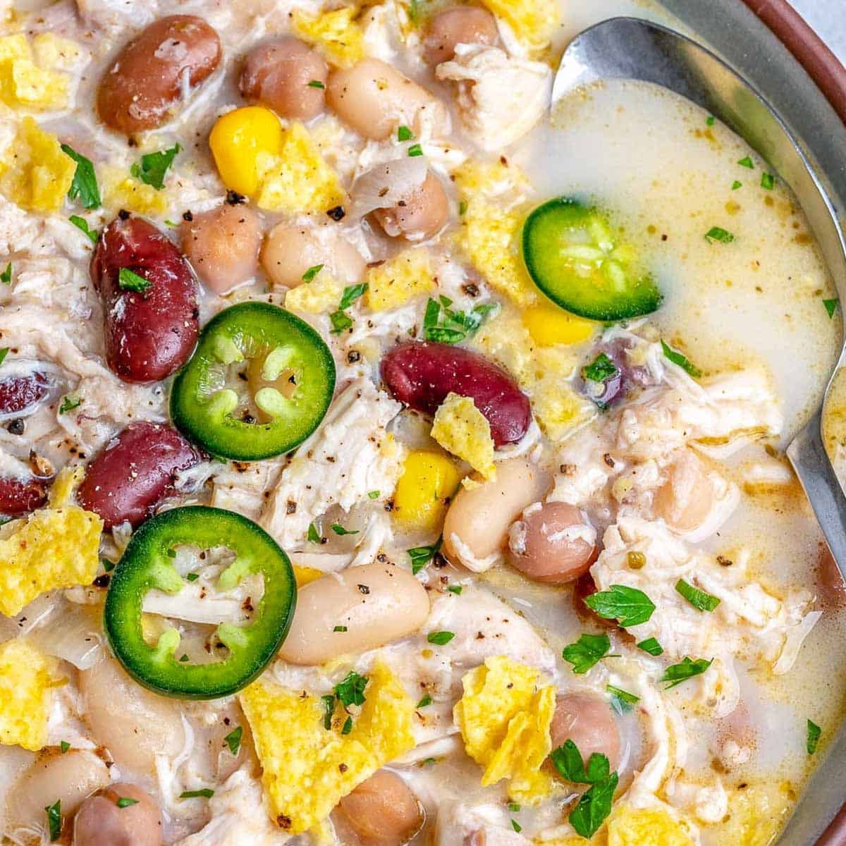a bowl with white chicken chili topped with sliced jalapeno.