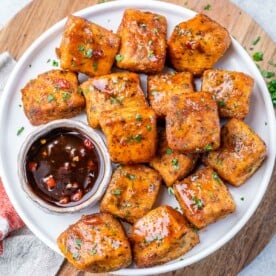 top view salmon bites on a plate with a small bowl of sauce