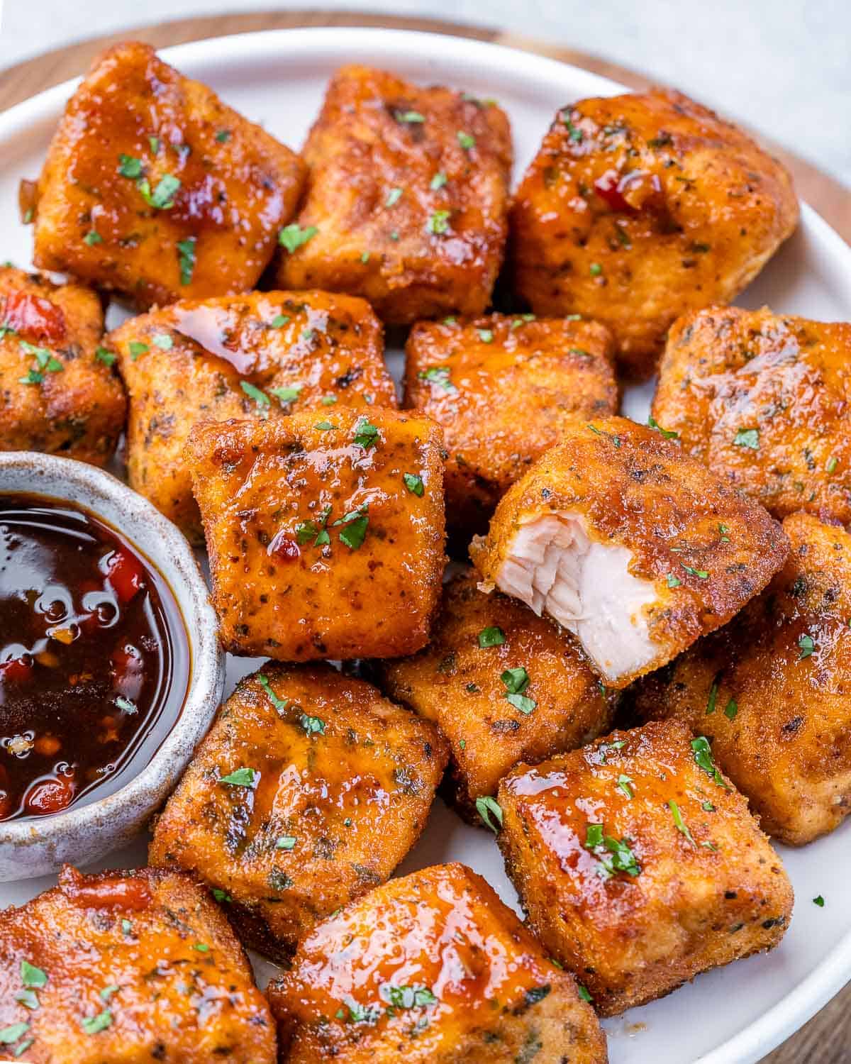 Air fryer salmon bites stacked on a white plate.