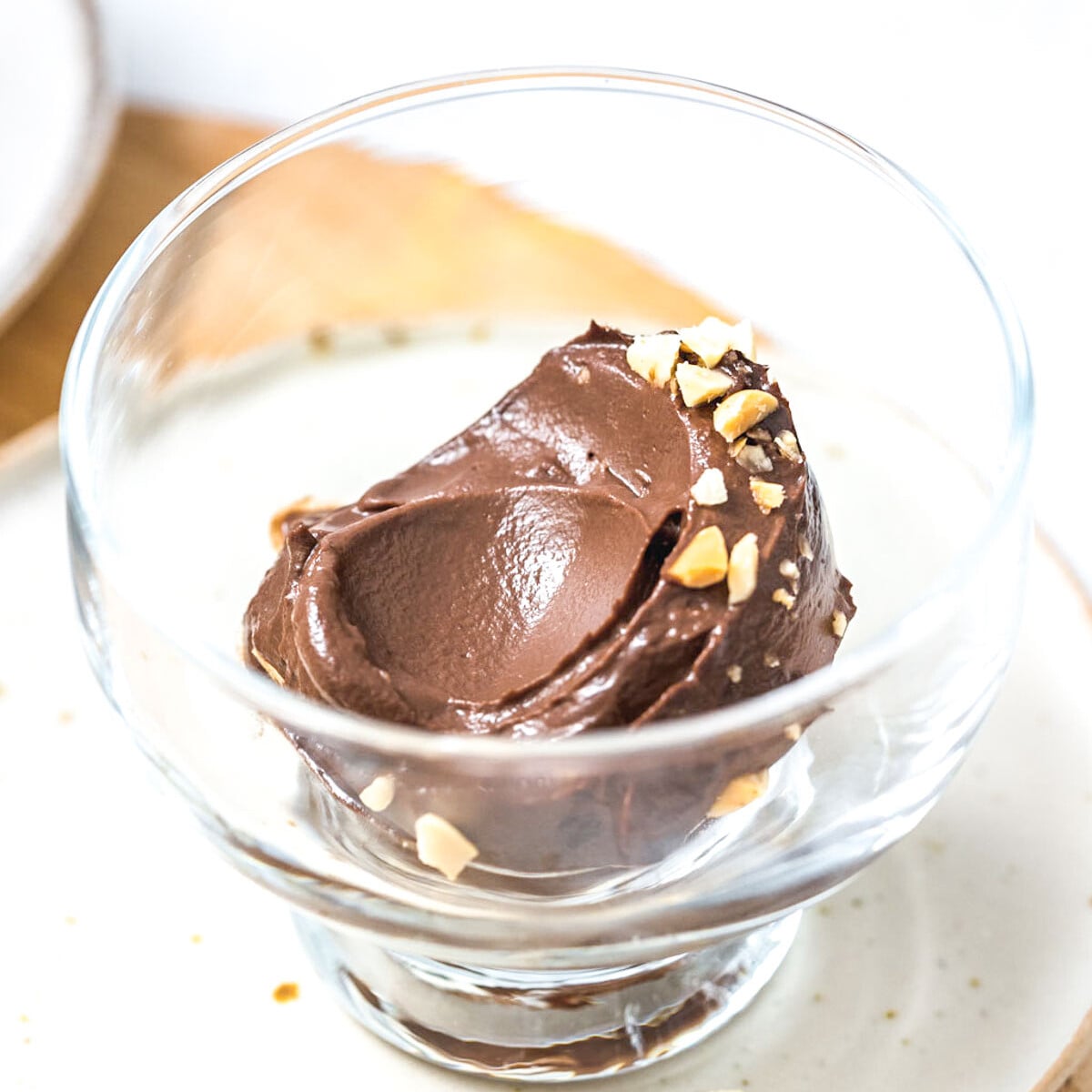 a glass bowl with avocado ice cream topped with chopped peanuts.