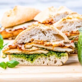 Chicken Parmesan Sandwiches sliced and arranged on a cutting board, served with fresh basil and a rustic look.