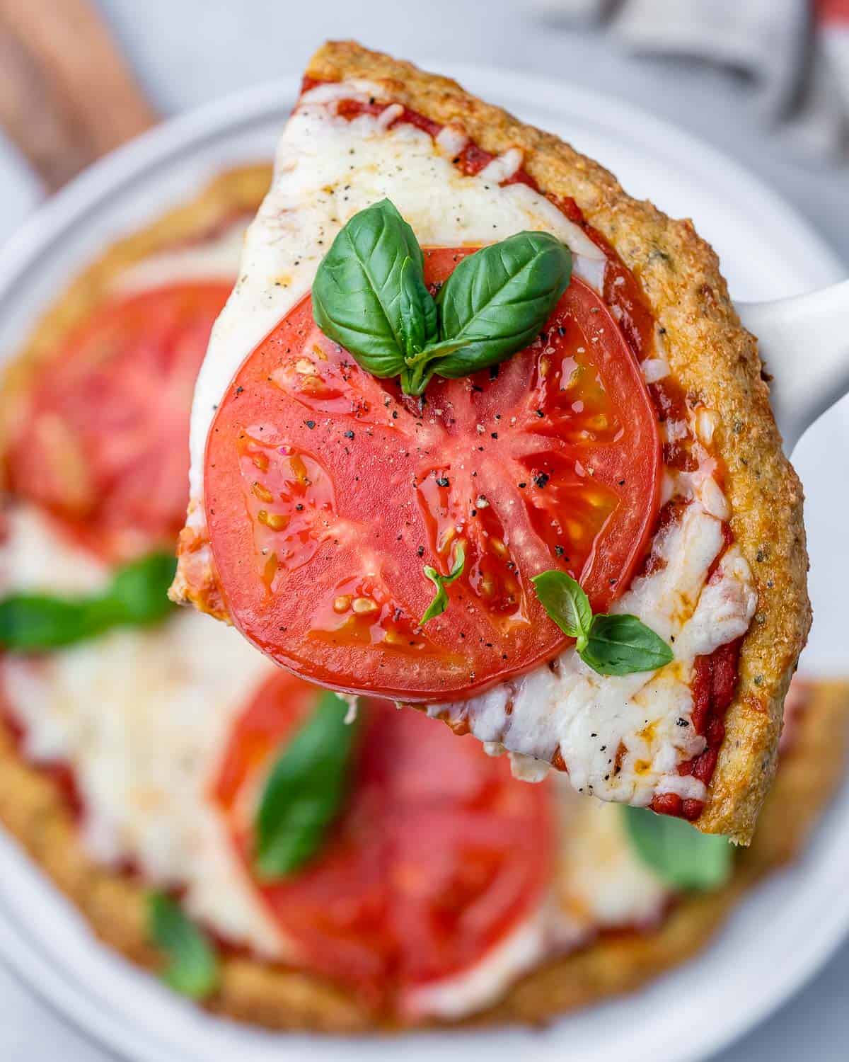 Holding up a slice of pizza on a spatula.