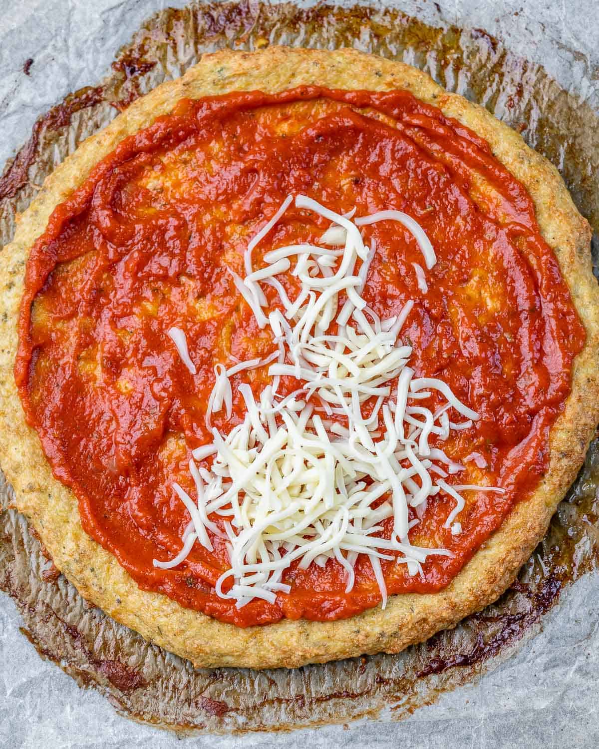 Pizza crust topped with marinara and mozzarella.