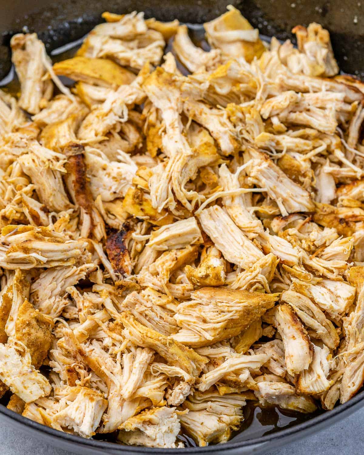 Shredded chicken cooking in a pan.