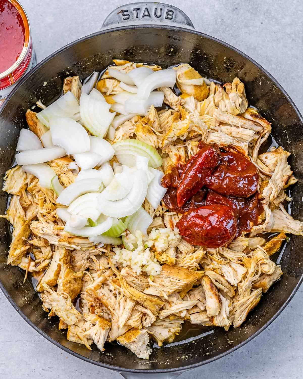 Add chipotle peppers and onions to shredded chicken.