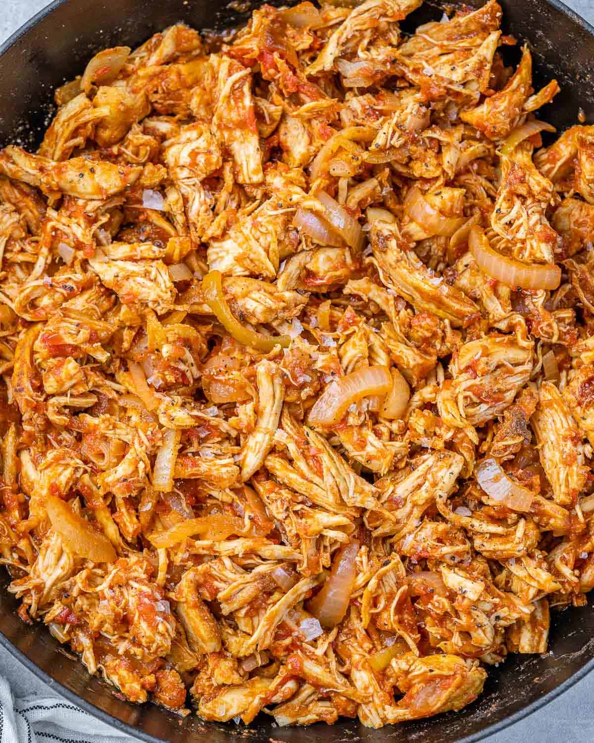 Chicken Tinga cooking in a large skillet.