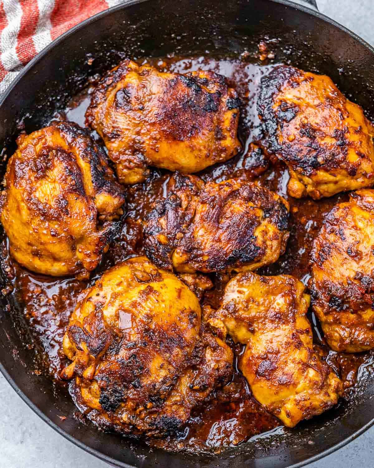 cooked chicken al pastor thighs in a dark round skillet.