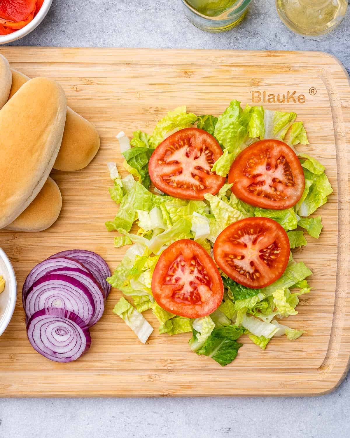 Lettuce, tomato and onions on a cutting board.