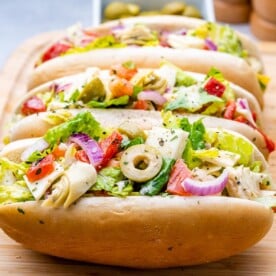 buns filled with chopped Italian salad on a cutting board.